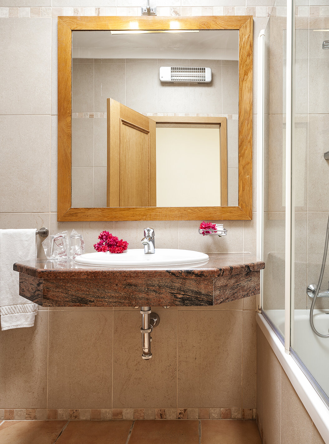 O Apartamento T1 - Terra do Pestana Palm Gardens tem uma banheira com chuveiro, um lavatório com flores e um espelho