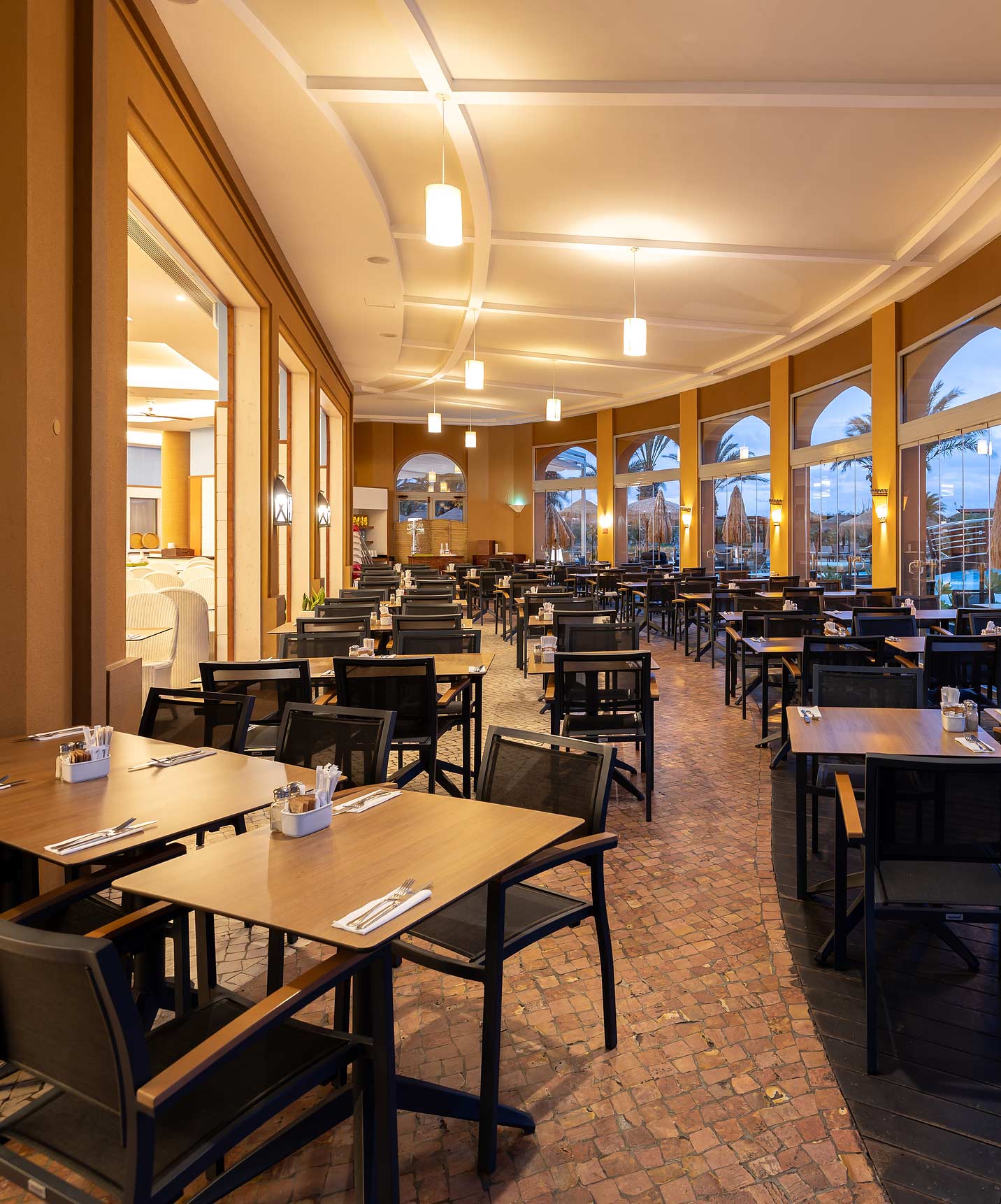 Sala de refeições informal do Pestana Porto Santo All Inclusive com várias mesas quadradas e cadeiras