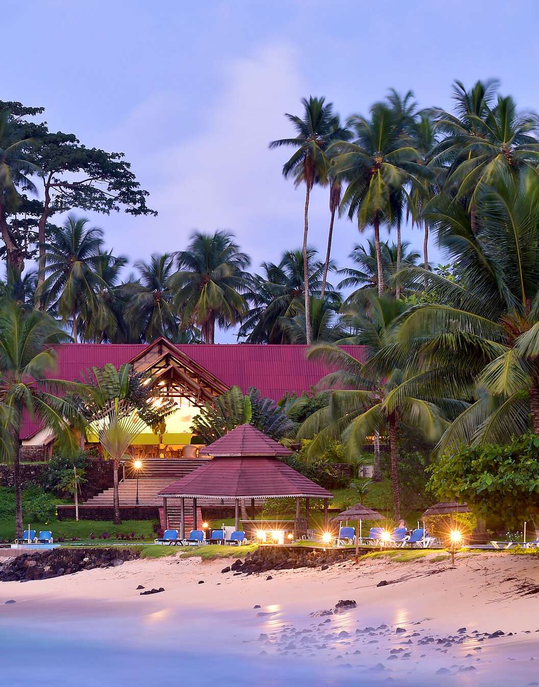 Praia e edifício com espreguiçadeiras e palmeiras do Pestana Equador, Hotel no Ilhéu das Rolas, em São Tomé