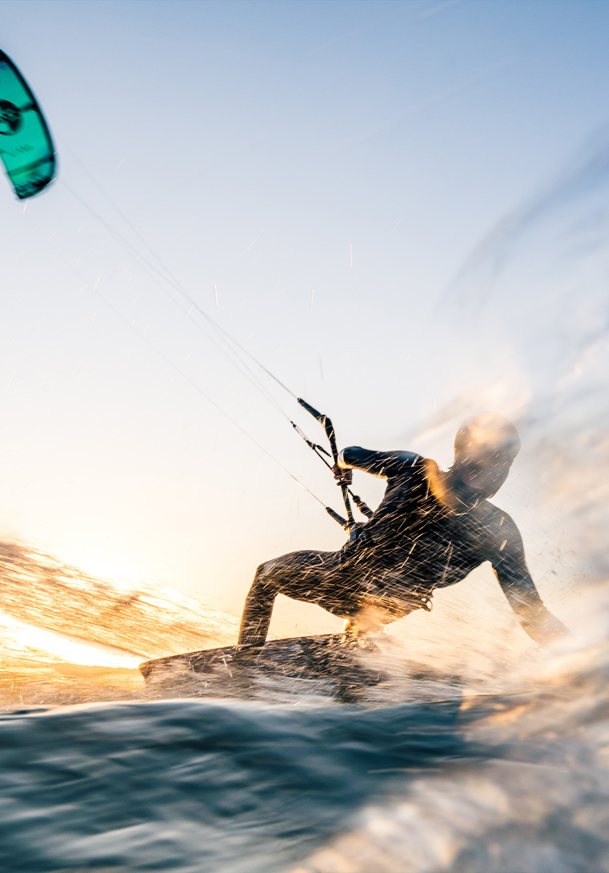Jongen kite-surfend op het blauwe water van de Algarve, glijdend over de golven met een kleurrijke kite in de heldere lucht