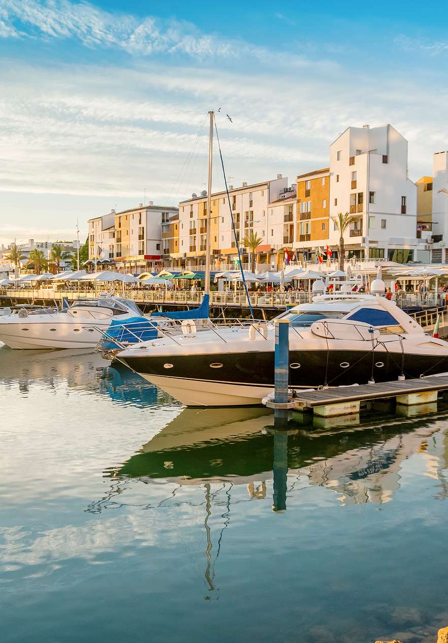 Vilamoura Marina in de Algarve bij zonsondergang, met boten van verschillende groottes en stijlen in kalm water