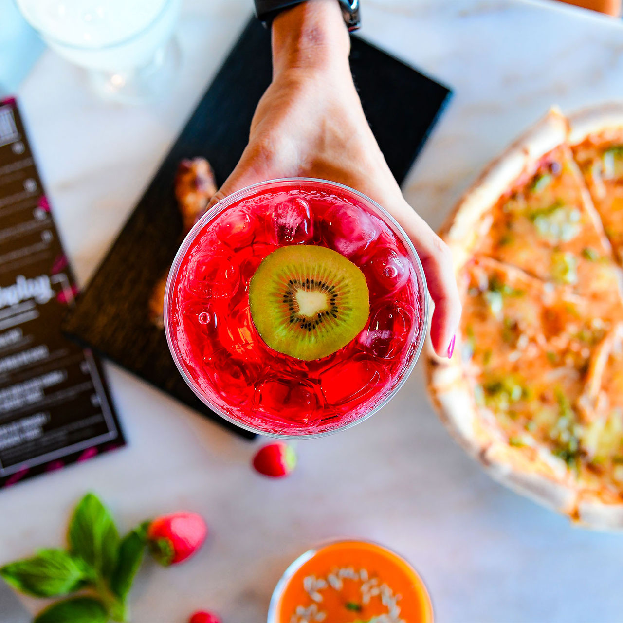 Luchtfoto van roze cocktail met kiwi en pizza in Pestana CR7 Funchal