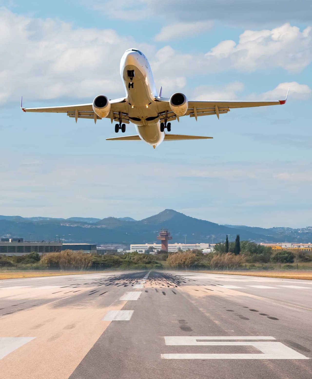 Groot commercieel vliegtuig stijgt op van een landingsbaan in Barcelona, met de controletoren op de achtergrond