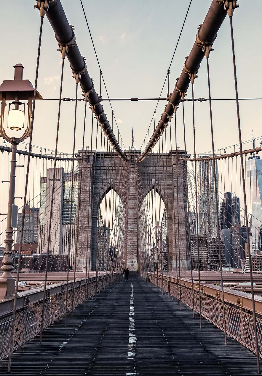 Panoramisch uitzicht op de Brooklyn Bridge, met stalen kabels en een ijzeren structuur onder een helderblauwe lucht