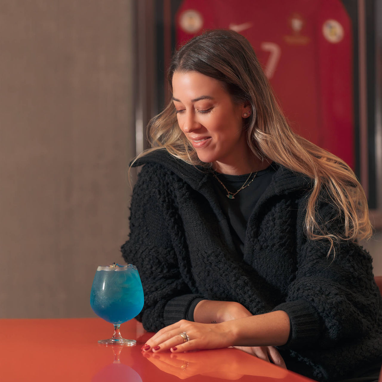 Vrouw met cocktail, met Cristiano Ronaldo-shirt aan muur