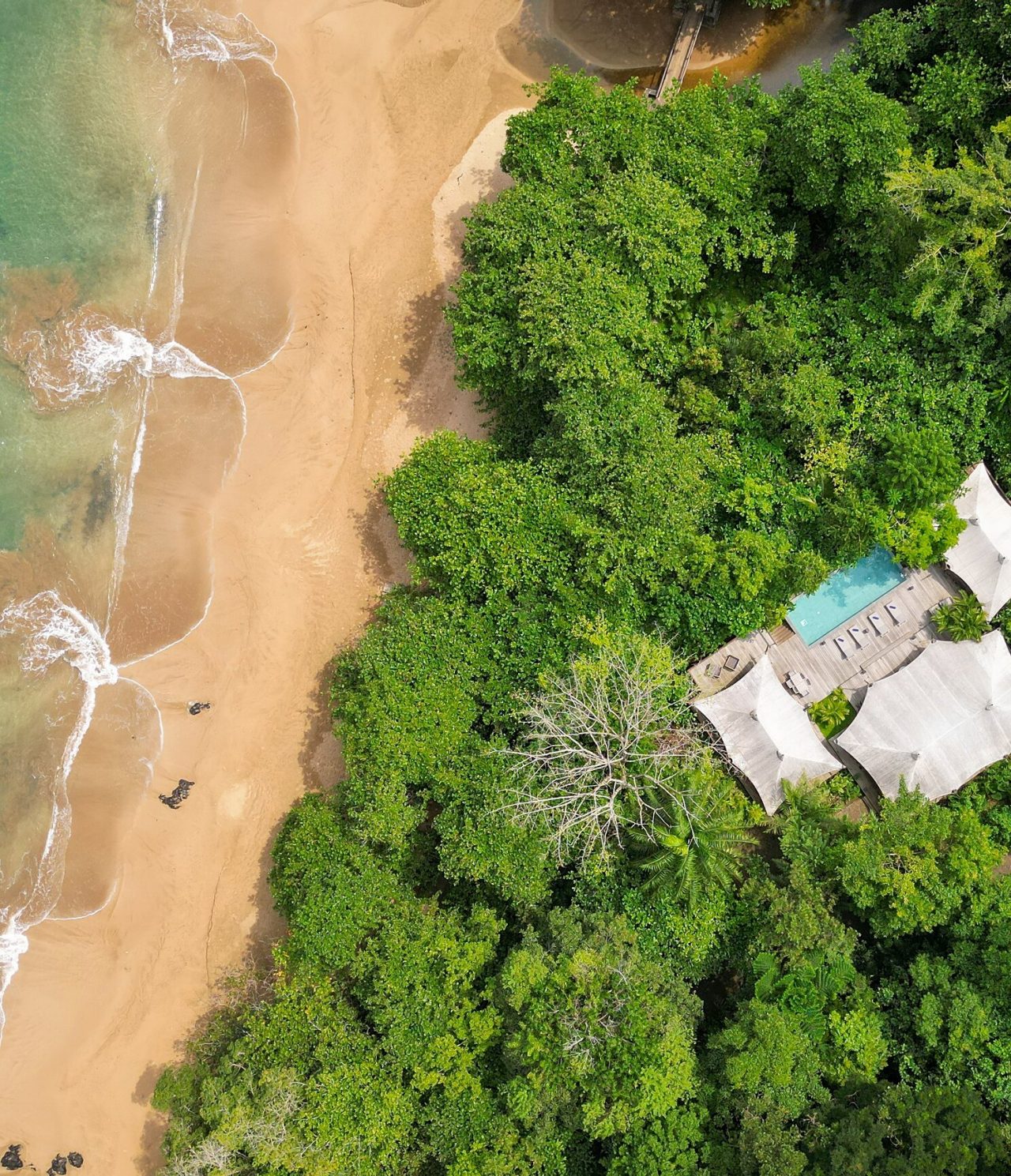 Aerial view of the island of São Tomé and Príncipe, building with a pool and a white sandy beach with crystal-clear waters