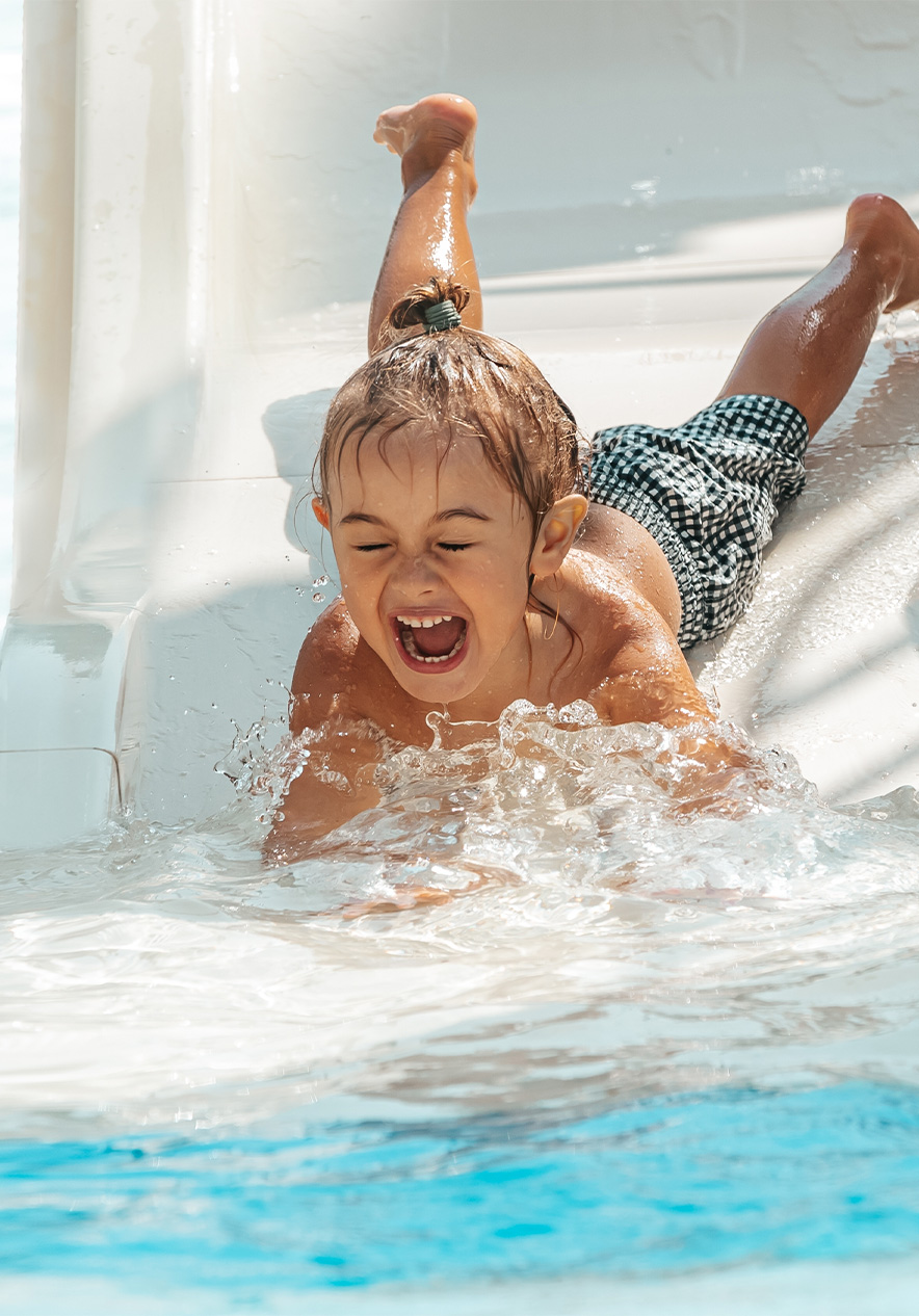 Child smiling while sliding down a water slide at Slide & Splash in the Algarve