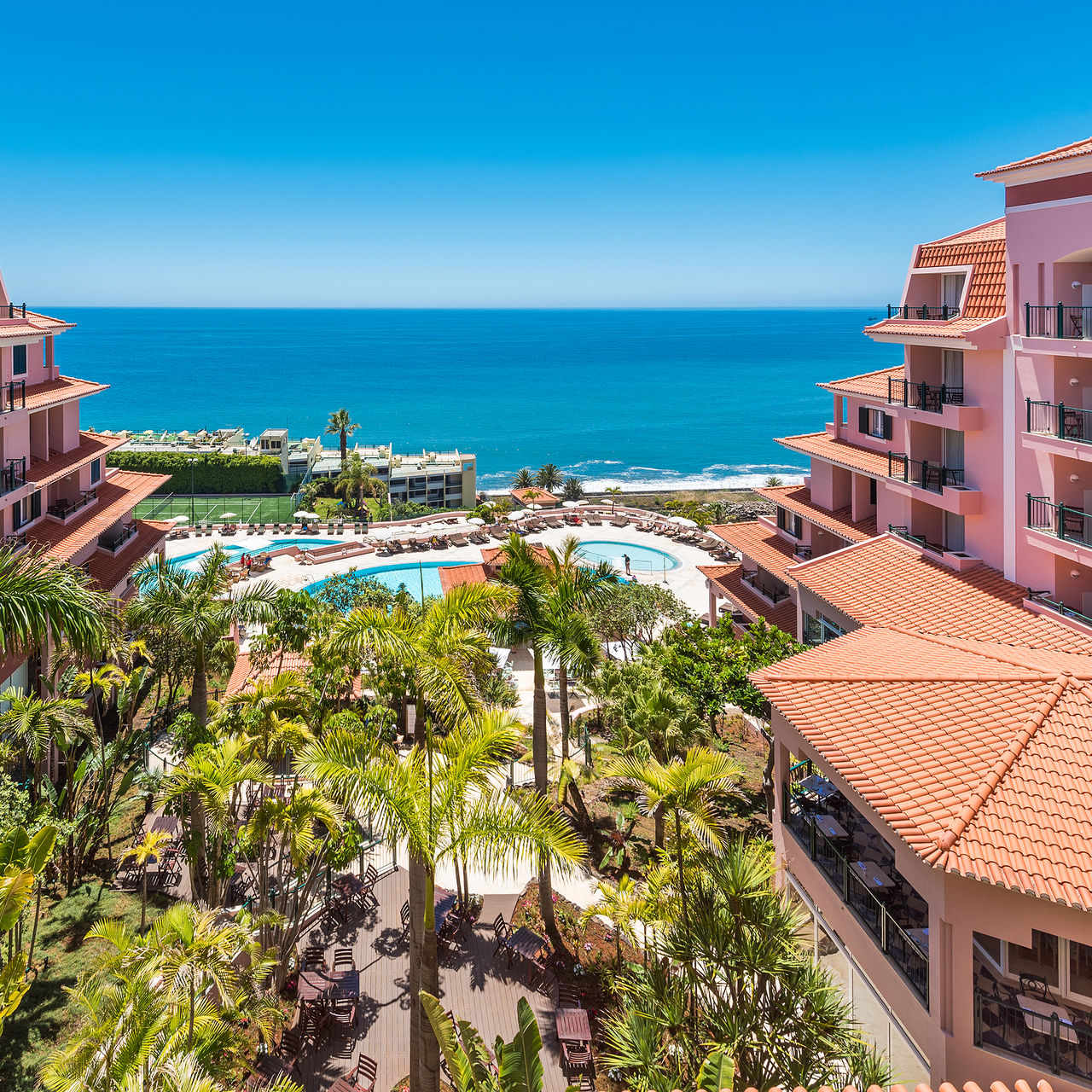 Panoramic view of Pestana Royal All Inclusive, with the outdoor pool and tennis court in the center, and the sea in the back