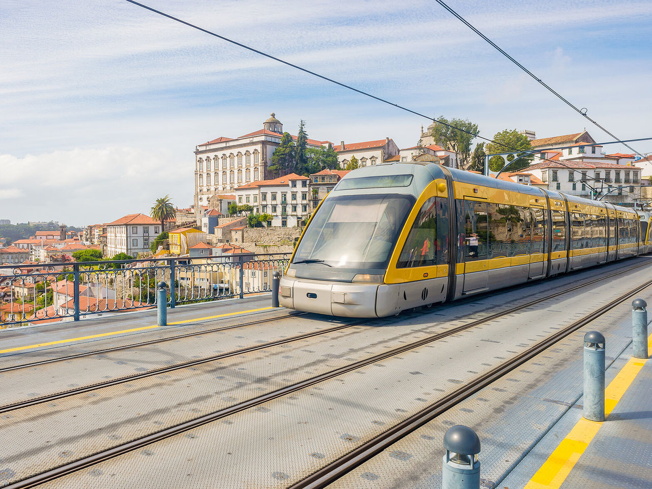 View of a modern yellow tram with the historic city of Porto in the background, characterized by tall and colorful buildings